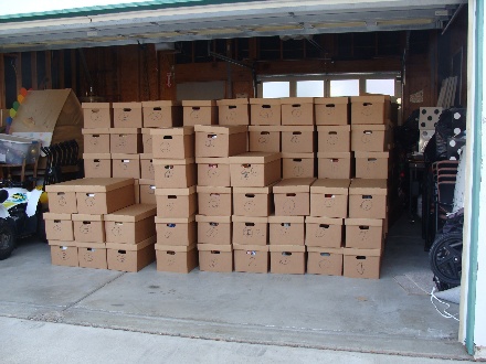 A large stack of boxes in a garage

Description automatically generated